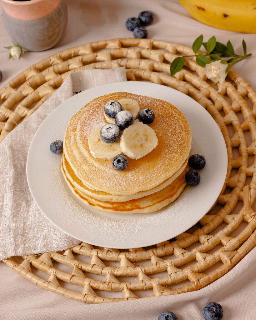 Pancakes topped with sliced bananas and blueberries
