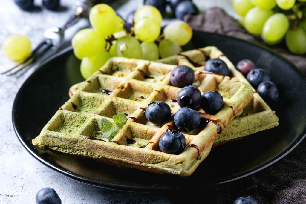 Square Green Waffles on a plate with grapes and blueberries